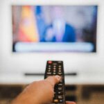 Fernbedienung vor einem Fernseher als Symbolbild für GlücksSpirale und TV-Bekanntgabe
